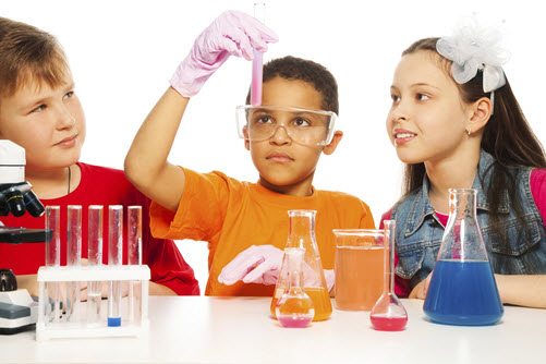 Zwei Jungen und ein Mädchen experimentieren am Tisch mit Labor-Gefäßen