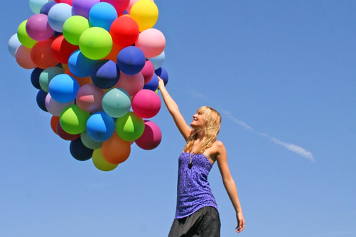 Junge Frau mit bunten Luftballons