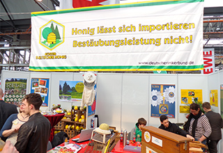 Der Stand der Schülerfirma "Dr. Nektar" mit großem Banner mit der Aufschrift "Honig lässt sich importieren - Bestäubungsleistung nicht!"