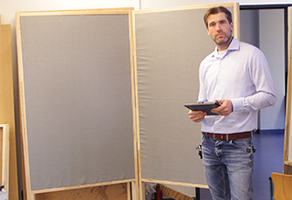 Mann mit weißem Hemd vor einer grauen Tafel - der Projektleiter der Schülerfirma "Leisebox"