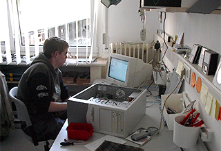 Ein Schüler der Schülerfirma "TuN e.V." an einem Schreibtisch mit einem Monitor und einem aufgeschraubten Rechner