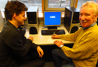 Schüler mit einem älteren Herrn bei einem Kurs zur Handhabung des PCs
