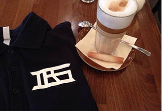 T-Shirt von Dr. Sokollovski Fashion liegt auf Tisch, daneben ein Latte Macchiato