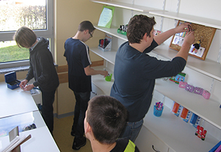 Schüler vom Team StifteBox sortieren Schreibwaren ins Verkaufsregal