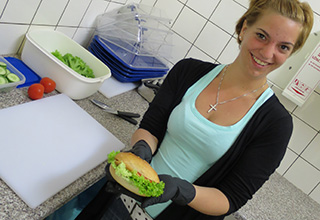 Mitglied vom Team schoolbucks in der Küche beim Belegen eines Brötchens