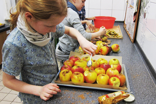Mädchen bereitet Backäpfel auf einem Backblech vor