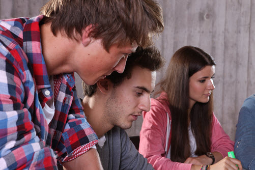 Eine Schülerin und zwei Schüler sitzen gemeinsam an einem Tisch und denken über eine Existenzgründungsidee nach
