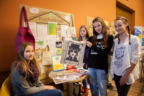 Vier Schülerinnen präsentieren ihre Produkte vor einem Stand