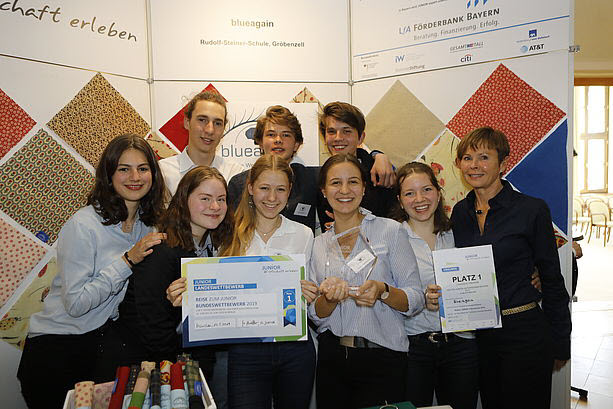 Gruppenbild von Schülerinnen und Schülern mit Urkunde auf der Bühne beim JUNIOR-Landeswettbewerb in Bayern