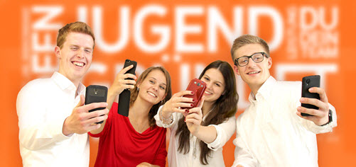 Zwei lachende Schülerinnnen und zwei Schüler mit einem Smartphone in der Hand