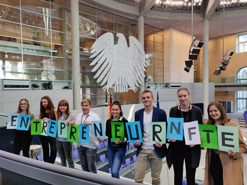 Schülerinnen und Schüler stehen im Bundestag vor dem Bundesadler und halten Buchstaben hoch, die das Wort Entrepreneurship ergeben