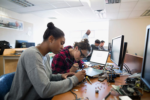 Gruppe Schüler in einem Werkraum schraubt an Elektrogeräten