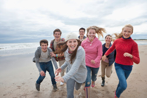 Gruppe lachender Schüler laufen am Strand