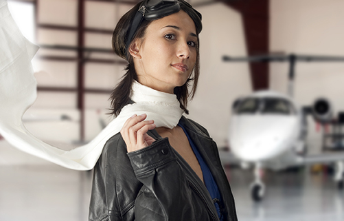 Junge Frau mit Fliegerbrille in Flugzeughalle