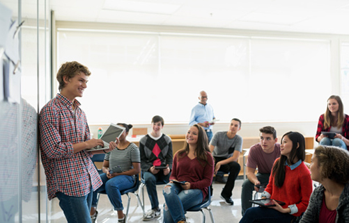 Schüler präsentiert eine Geschäftsidee vor anderen Schülern, die im Klassenraum in einem Sitzkreis sitzen