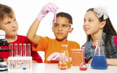 Link zur Seite „Hintergrund“ (Zwei Jungen und ein Mädchen experimentieren am Tisch mit Labor-Gefäßen)
